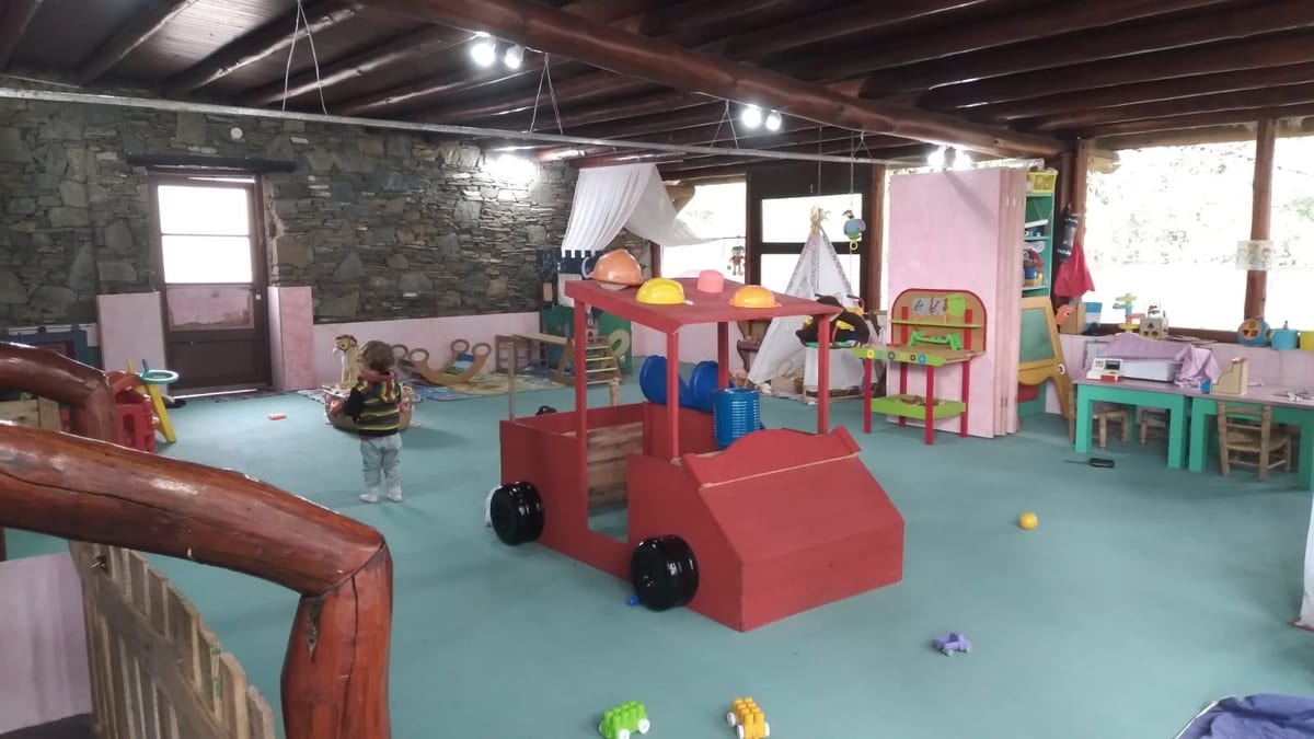 Sala de juegos con auto de madera rojo y materiales de taller